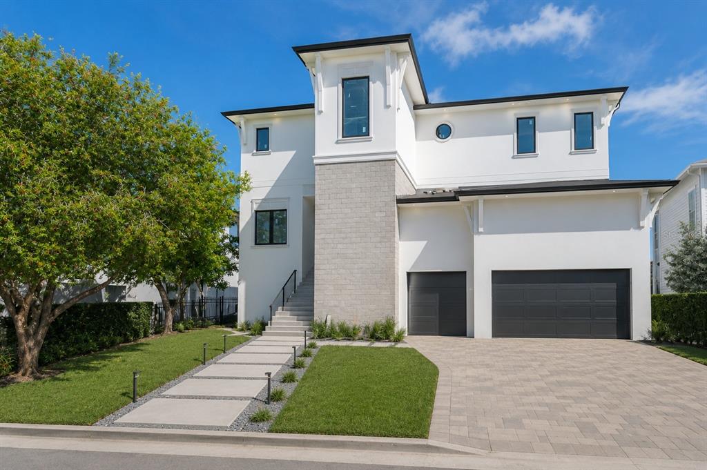 A modern two-story house with a stone facade, white exterior, and a paved driveway — 654 GENEVA PLACE, TAMPA, FL
