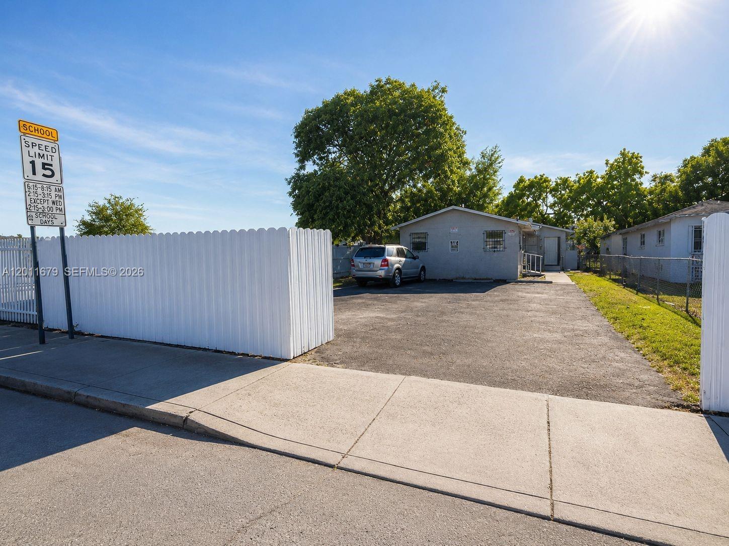 A single-story house with a paved driveway sits behind a white picket fence — 6228 NW 4th Ave, Miami FL 33150, MIAMI, FL