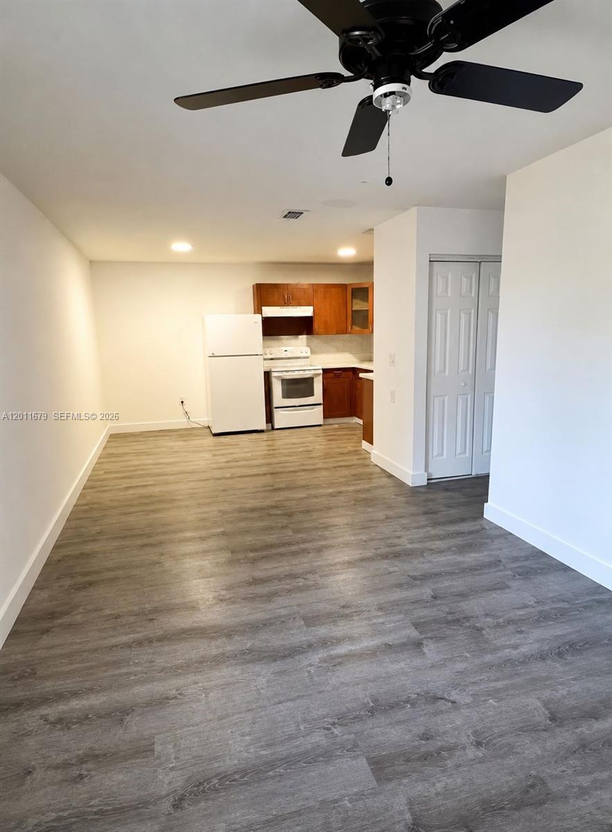 A kitchen with wood cabinets and white appliances opens into a living area with flooring — 6228 NW 4th Ave, Miami FL 33150, MIAMI, FL