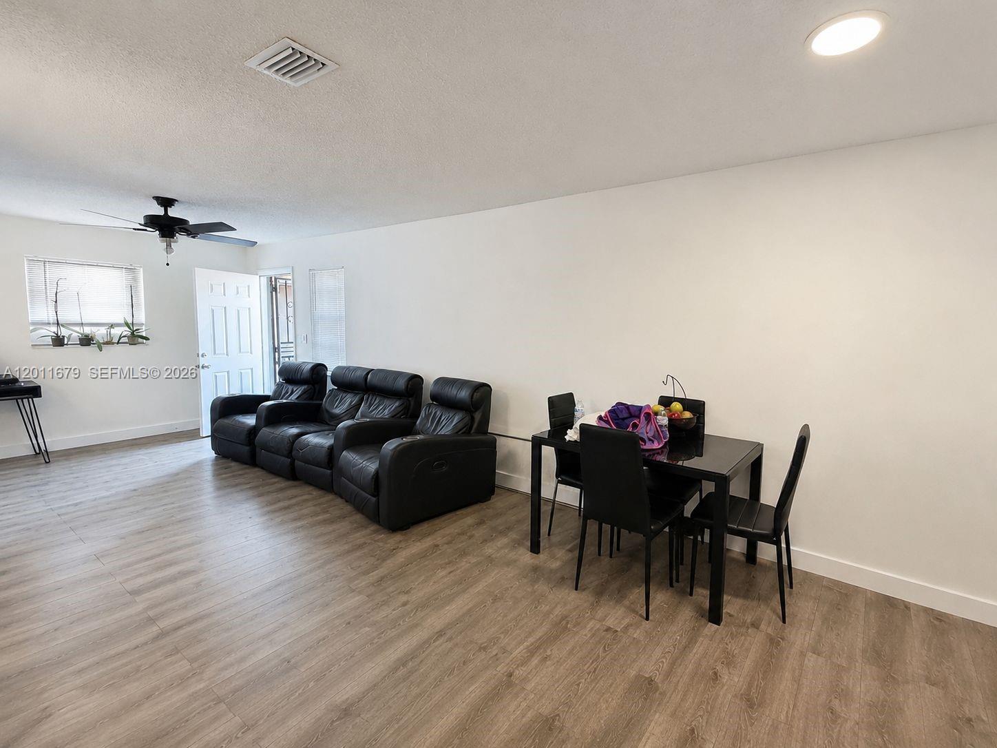 A living and dining area features wood-look flooring, a black leather sofa, and a dining set — 6228 NW 4th Ave, Miami FL 33150, MIAMI, FL