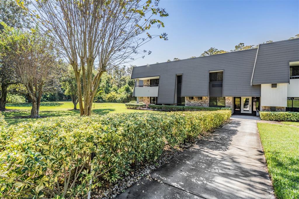 A concrete walkway leads to the entrance of a two-story building with gray siding — 36750 US HIGHWAY 19 N UNIT 6-214, PALM HARBOR, FL