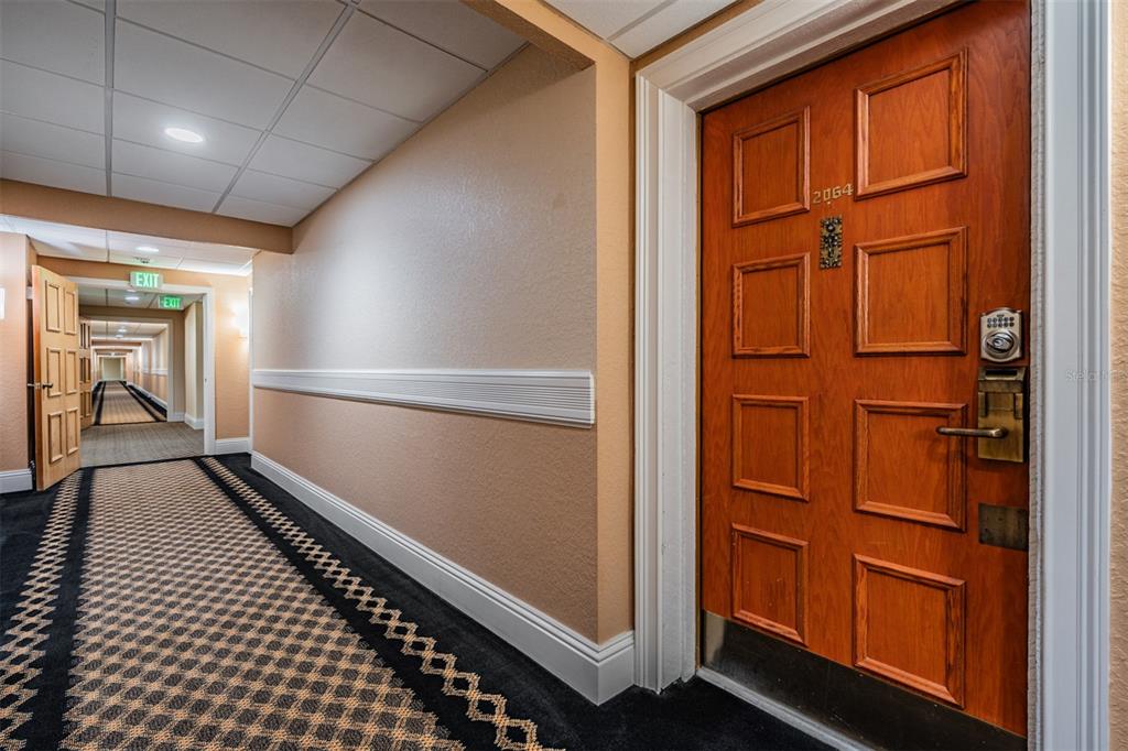 A hotel-style hallway features a wooden door numbered 2064, patterned carpet, and recessed lighting — 36750 US HIGHWAY 19 N UNIT 6-214, PALM HARBOR, FL