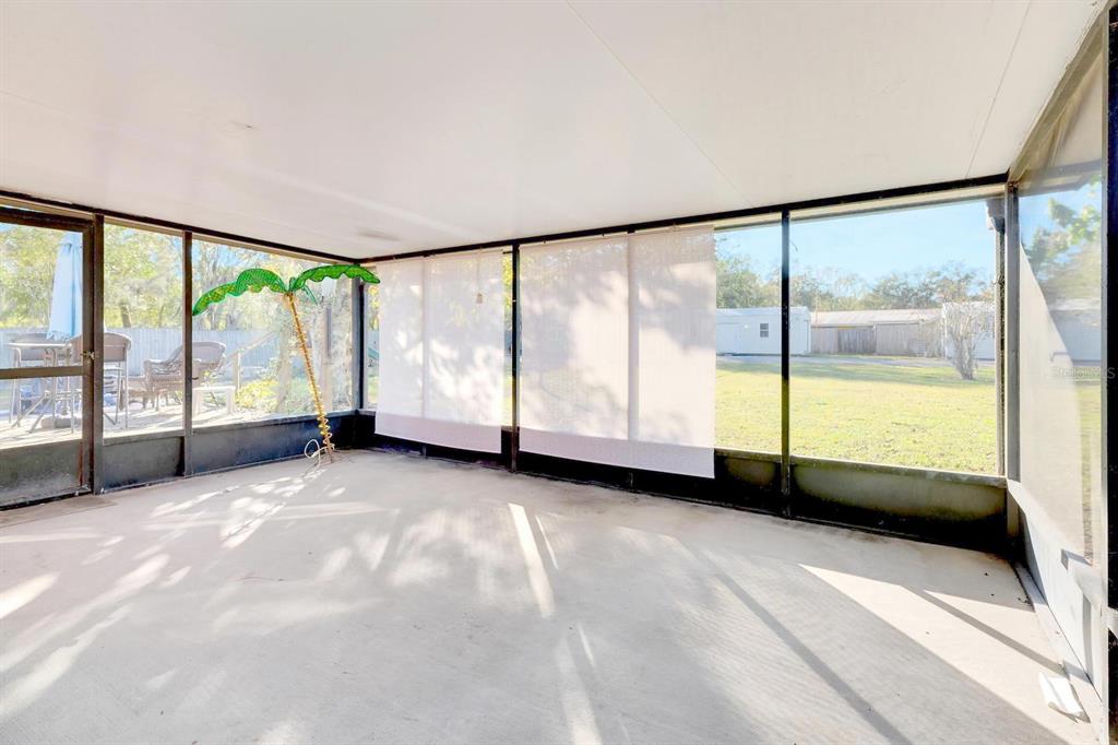 A screened-in porch with a concrete floor, white privacy shades, and a view of a yard — 5201 PLESS ROAD, PLANT CITY, FL
