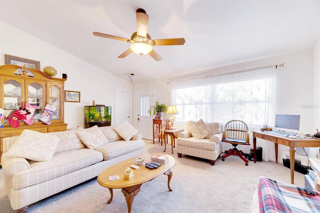 A living room features a beige striped sofa, a wooden coffee table, and a desk — 5201 PLESS ROAD, PLANT CITY, FL