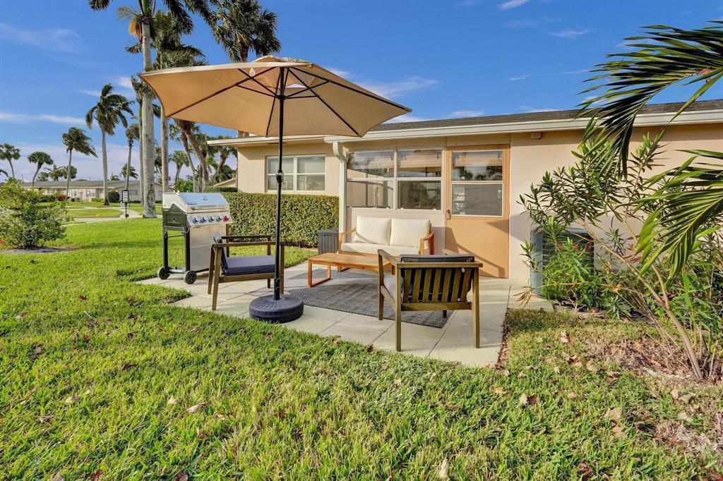 A patio with outdoor furniture, a grill, and a tan umbrella sits outside a house — 2592 E Dudley Dr Drive E # A, West Palm Beach FL 33415, WEST PALM BEACH, FL