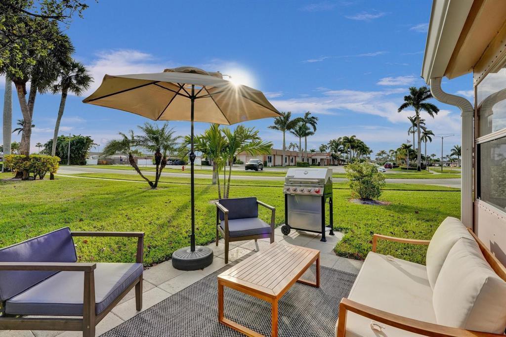 A patio with outdoor furniture, a grill, and an umbrella overlooks a grassy lawn — 2592 E Dudley Dr Drive E # A, West Palm Beach FL 33415, WEST PALM BEACH, FL