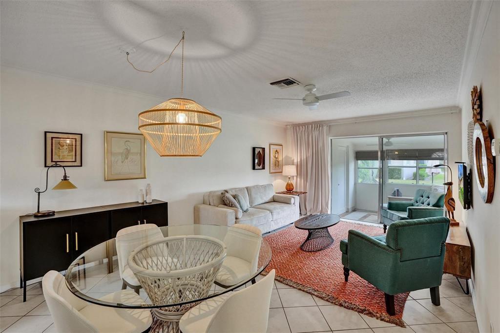A living and dining area features a glass table, teal armchairs, and a woven pendant light — 2592 E Dudley Dr Drive E # A, West Palm Beach FL 33415, WEST PALM BEACH, FL