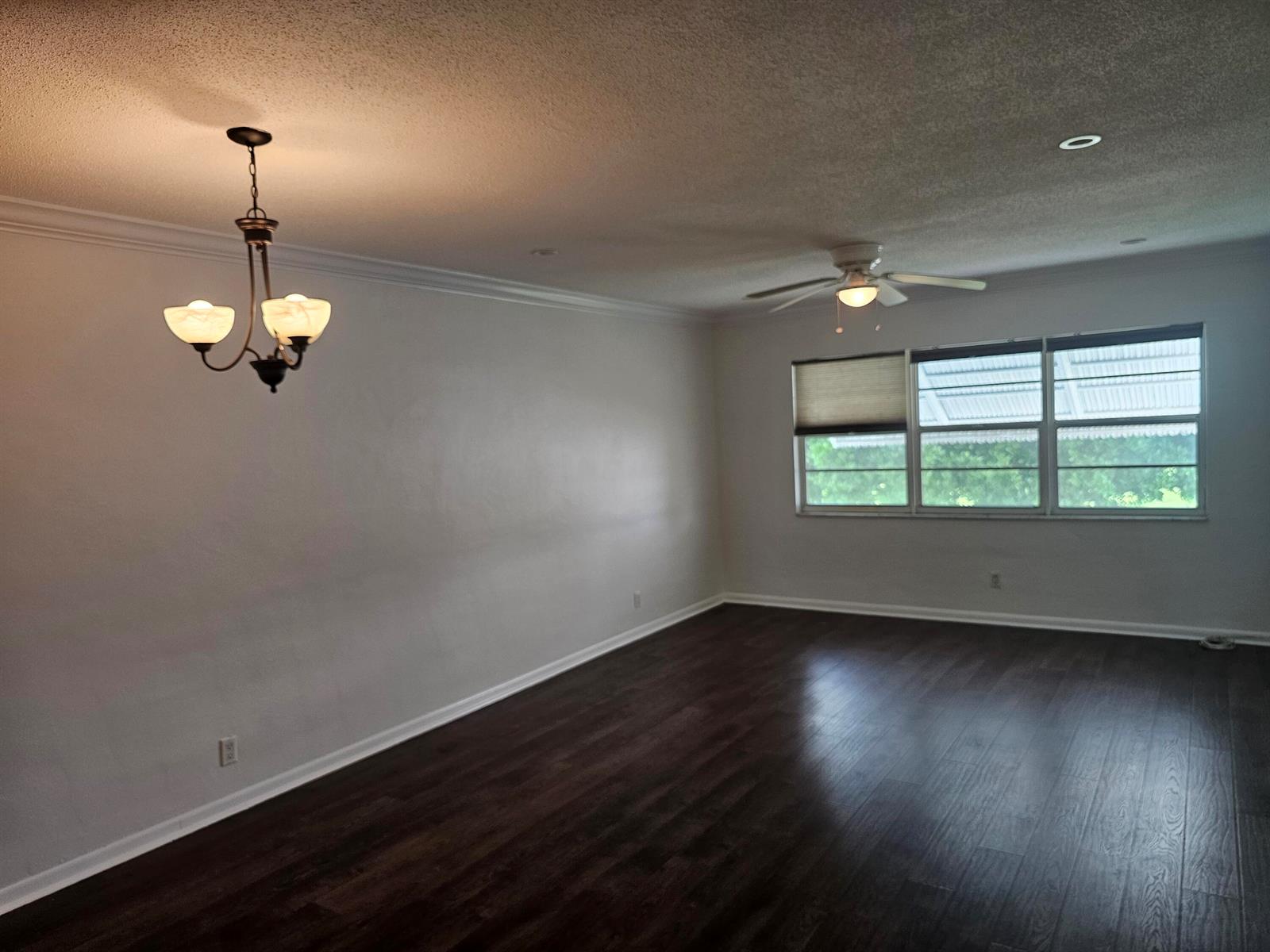 An empty room with dark wood flooring, a ceiling fan, and a hanging light fixture — 2851 E Golf Boulevard # 207, Pompano Beach FL 33064, POMPANO BEACH, FL