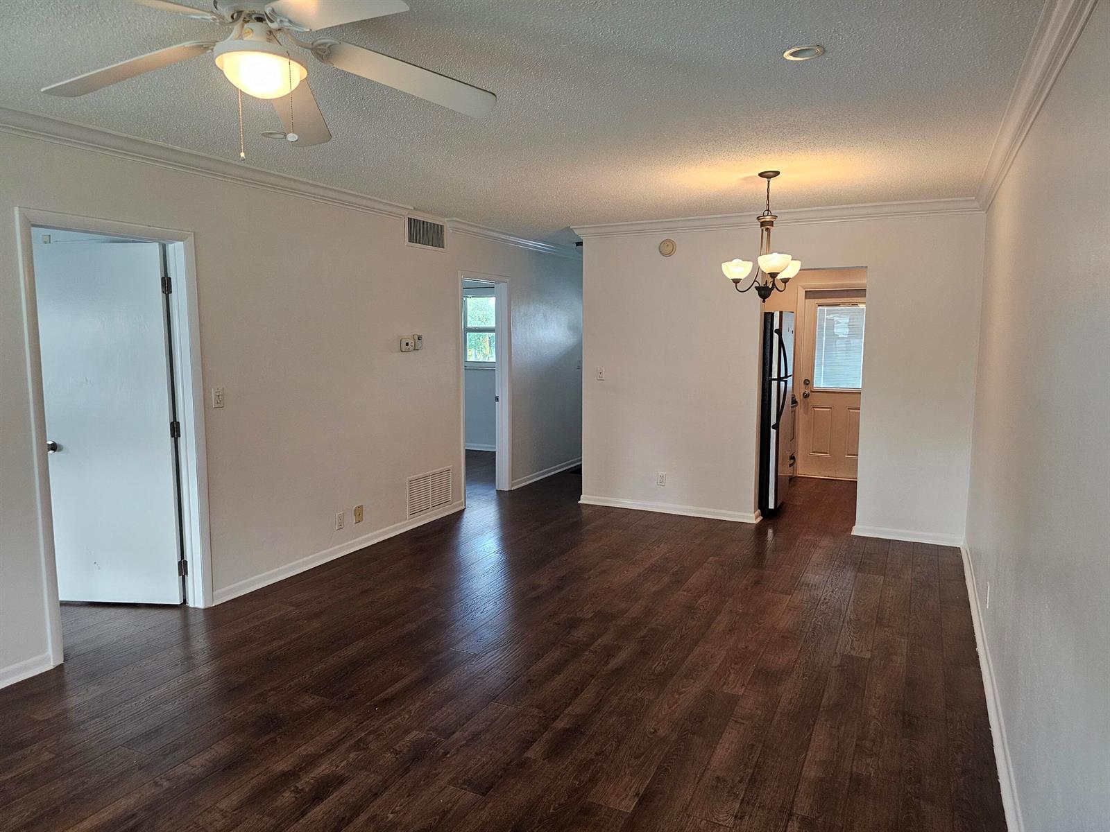 An empty room with dark wood-look flooring, white walls, a ceiling fan, and a chandelier — 2851 E Golf Boulevard # 207, Pompano Beach FL 33064, POMPANO BEACH, FL