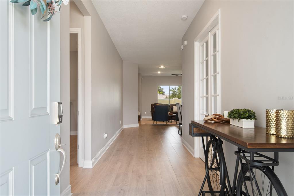 A hallway with light wood flooring leads from an entryway toward a living area — 19358 BANFIELD PLACE, ORLANDO, FL