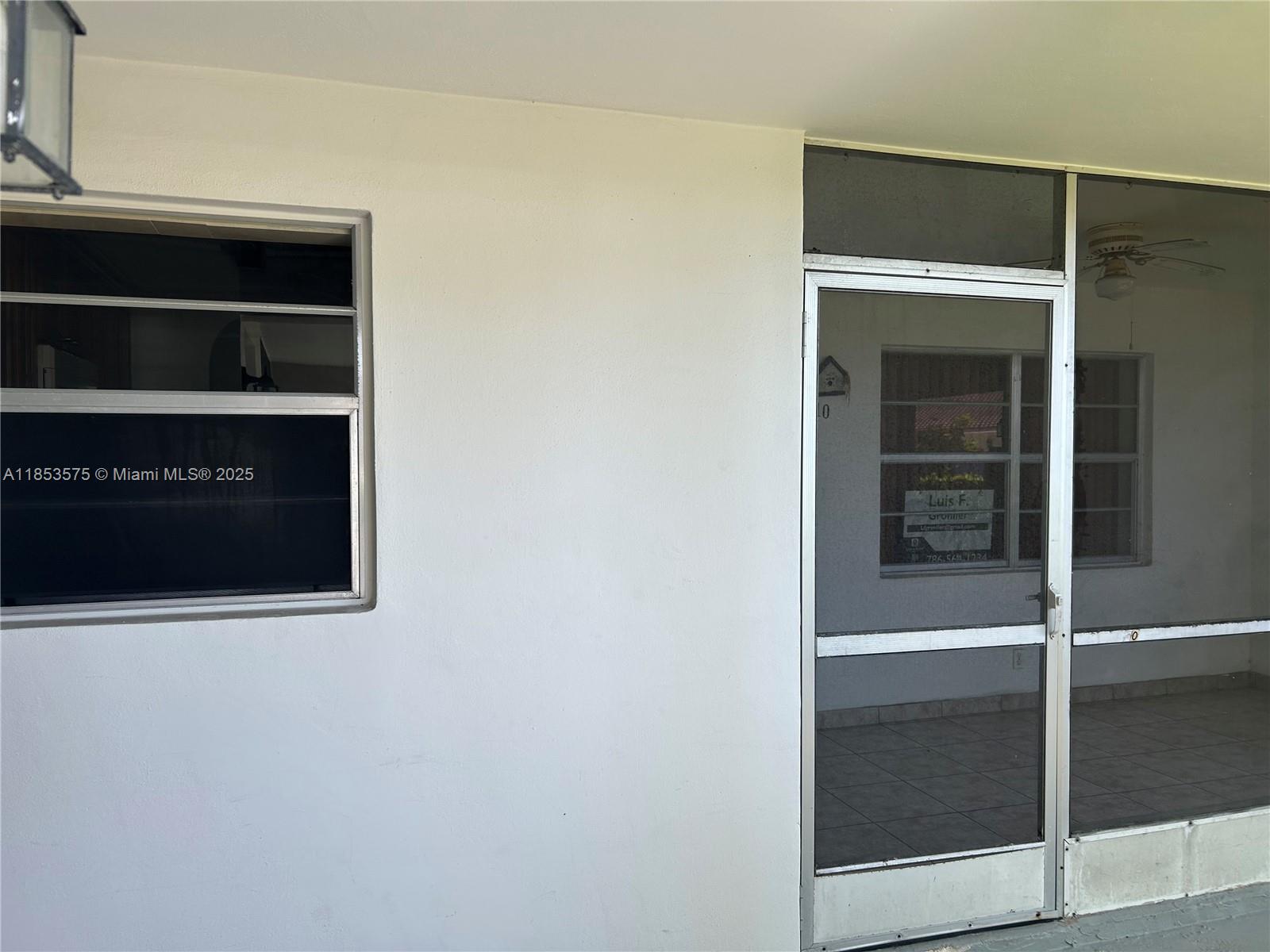 A white exterior wall features a jalousie window and a screen door leading inside — 501 Blue Heron Dr # A, Hallandale Beach FL 33009, HALLANDALE BEACH, FL