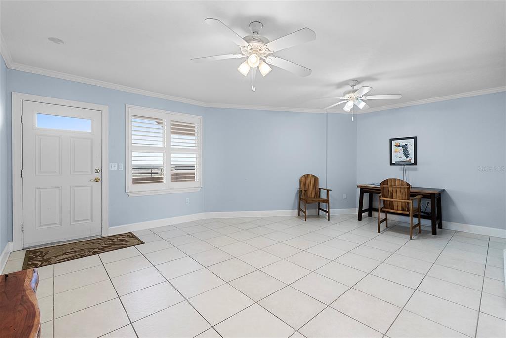 A light blue room features white tile floors, two ceiling fans, and a wooden desk — 3315 S ATLANTIC AVENUE UNIT 1806, DAYTONA BEACH SHORES, FL