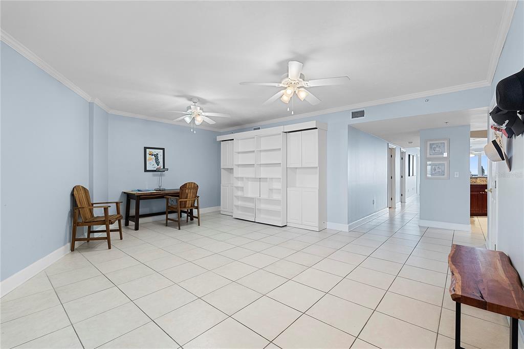 A spacious room with light blue walls, white tile flooring, two ceiling fans, and built-in cabinetry — 3315 S ATLANTIC AVENUE UNIT 1806, DAYTONA BEACH SHORES, FL