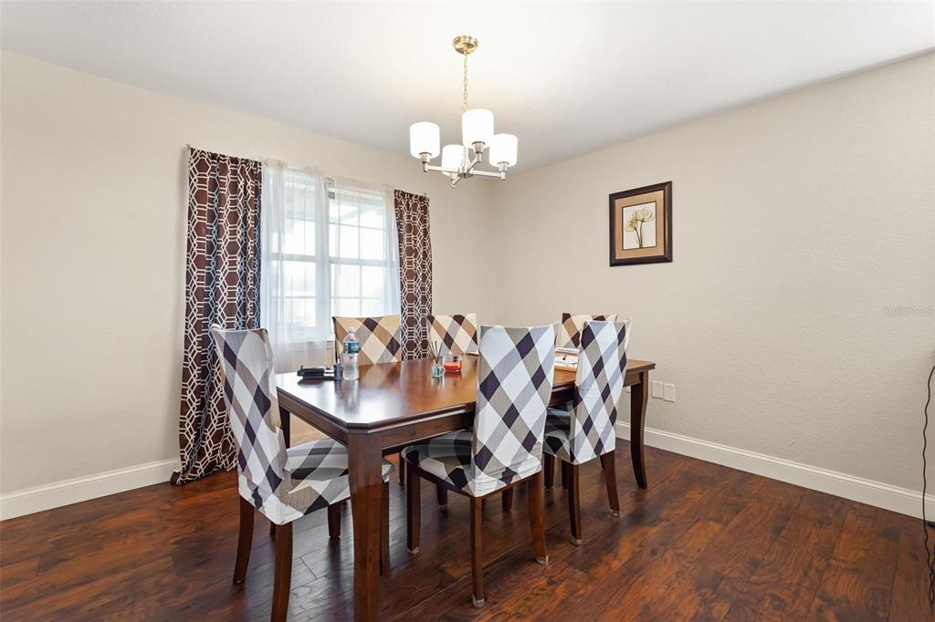 A dining room features a wooden table with plaid-covered chairs, a chandelier, and hardwood floors — 1922 MATTHEW COURT, LAKELAND, FL