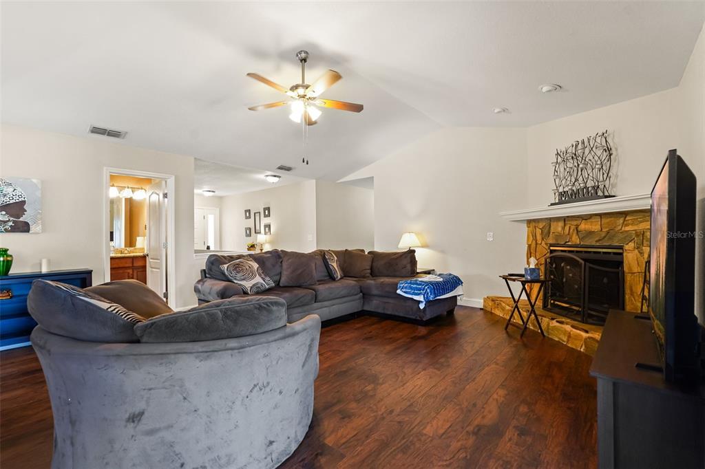 A living room features a stone fireplace, dark wood flooring, and a large sectional sofa — 1922 MATTHEW COURT, LAKELAND, FL