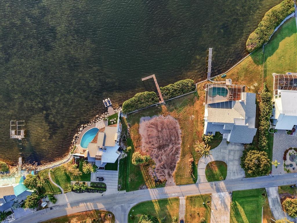 An aerial view shows two waterfront houses with pools separated by a vacant dirt lot — 2308 PALMA SOLA BOULEVARD, BRADENTON, FL