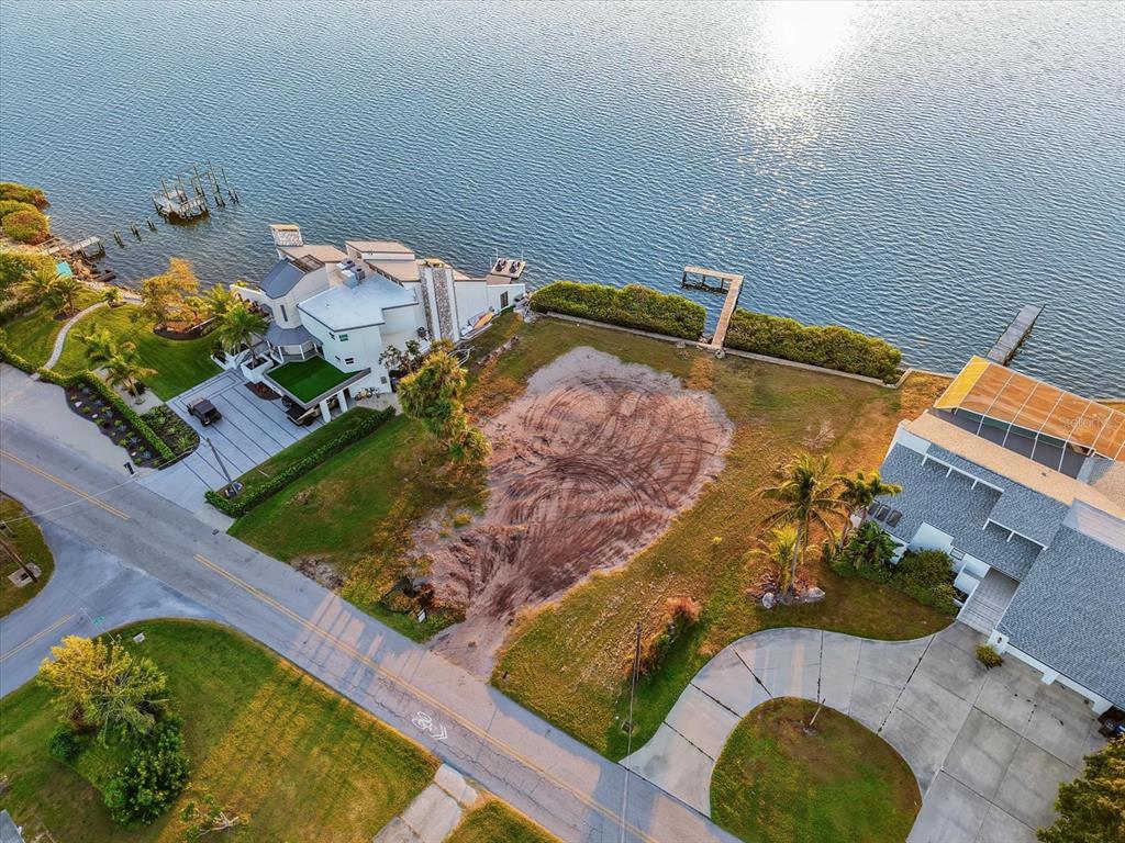 An aerial view shows a vacant waterfront lot situated between two residential houses — 2308 PALMA SOLA BOULEVARD, BRADENTON, FL