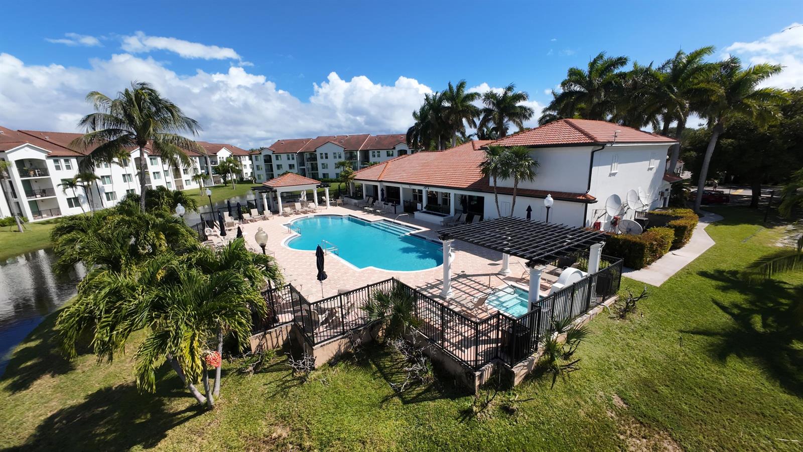 An aerial view shows a swimming pool and hot tub area surrounded by apartment buildings — 615 Villa Circle, Boynton Beach FL 33435, BOYNTON BEACH, FL