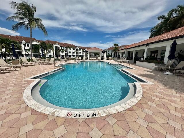 A swimming pool with a depth marker sits in a courtyard surrounded by apartment buildings — 615 Villa Circle, Boynton Beach FL 33435, BOYNTON BEACH, FL