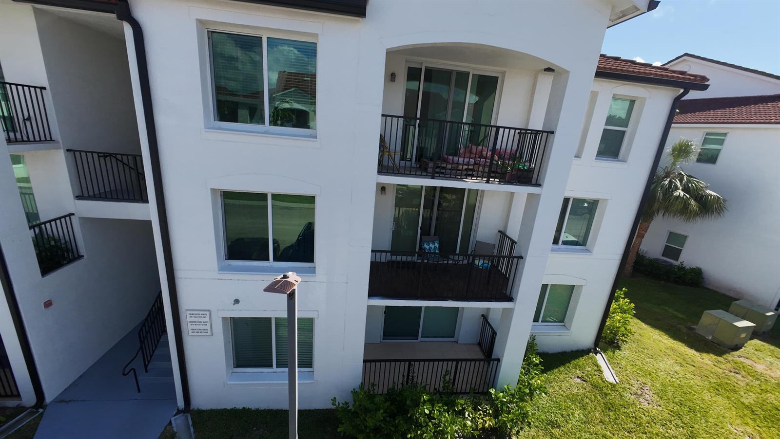 An exterior view of a three-story apartment building featuring balconies and white stucco walls — 615 Villa Circle, Boynton Beach FL 33435, BOYNTON BEACH, FL