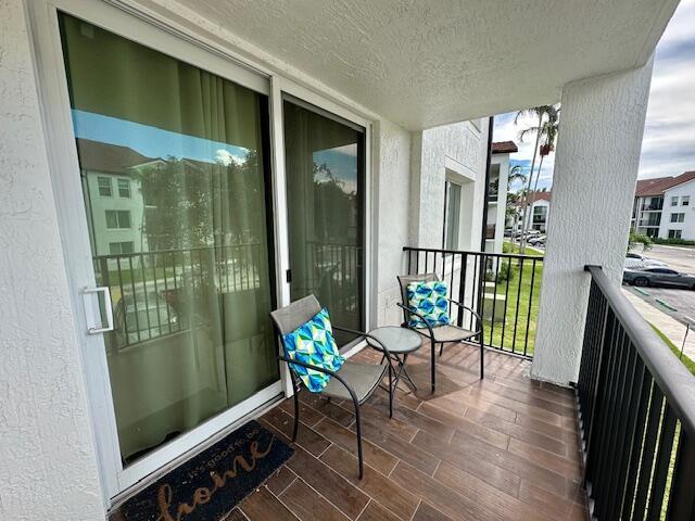 A balcony features two chairs with patterned pillows, a small table, and tiled flooring — 615 Villa Circle, Boynton Beach FL 33435, BOYNTON BEACH, FL
