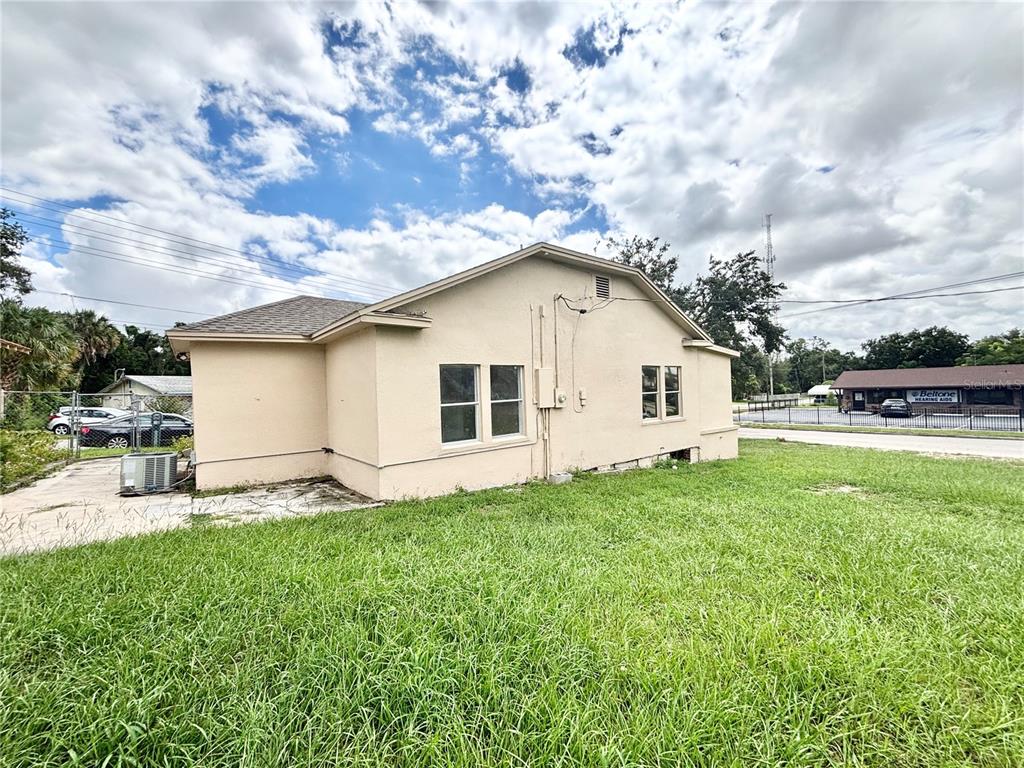 The exterior of a beige, single-story building with a shingled roof and a grassy yard — 1020 E MAIN STREET, HAINES CITY, FL