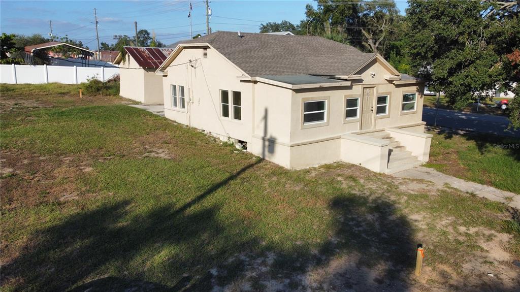 An aerial view of a tan, single-story house with a front porch and detached shed — 1020 E MAIN STREET, HAINES CITY, FL