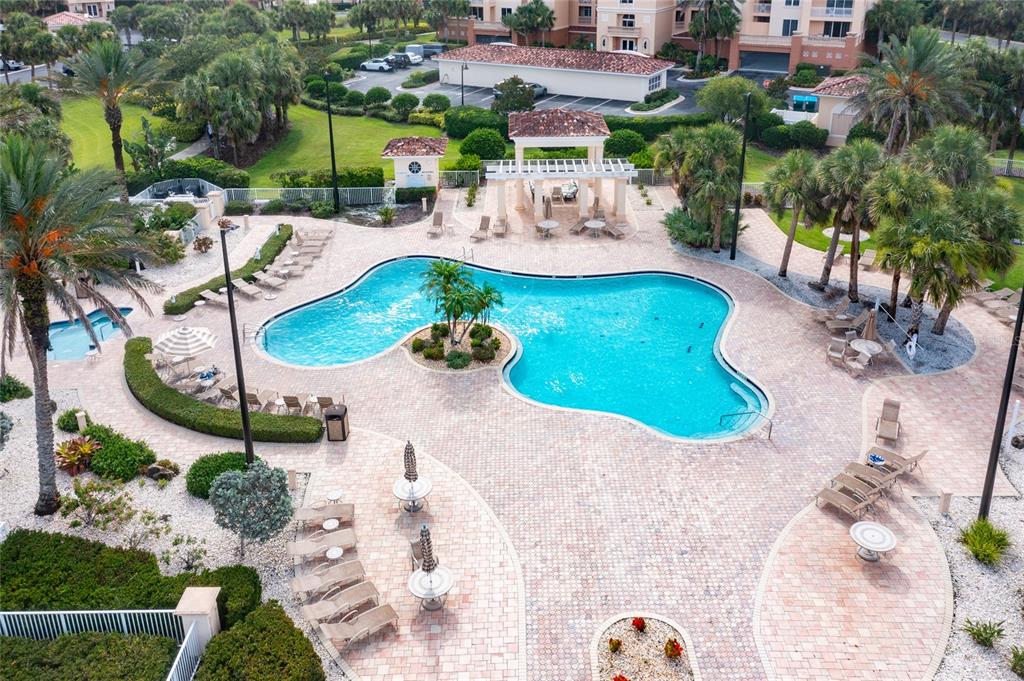 An aerial view of a resort-style swimming pool with a central island and surrounding patio — 250 MINORCA BEACH WAY UNIT 203, NEW SMYRNA BEACH, FL