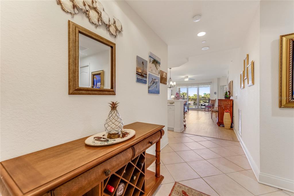 A hallway with tile flooring leads to an open living area with a balcony view — 250 MINORCA BEACH WAY UNIT 203, NEW SMYRNA BEACH, FL