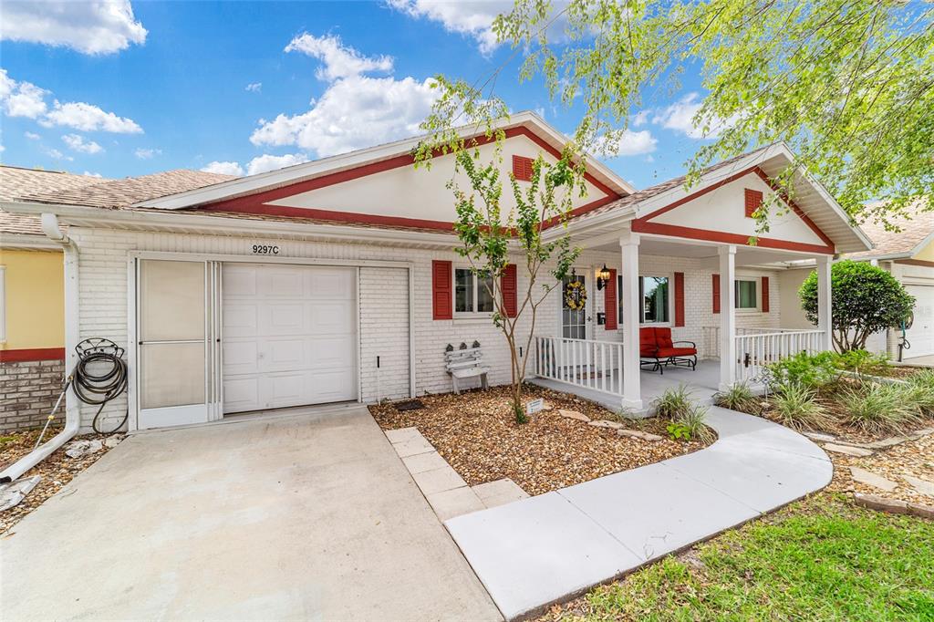 A single-story white brick house with red trim, a garage, and a covered front porch — 9297 SW 90TH COURT UNIT C, OCALA, FL
