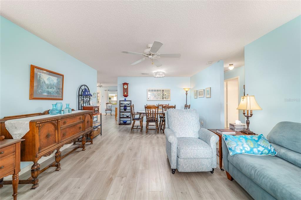 A living and dining area with light blue walls, wood-look flooring, and a ceiling fan — 9297 SW 90TH COURT UNIT C, OCALA, FL