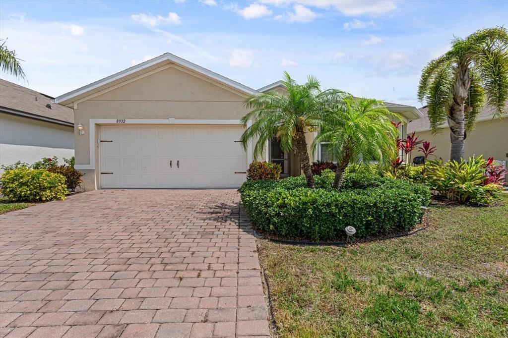A single-story house with a beige stucco exterior, a brick paver driveway, and palm trees — 8932 EXCELSIOR PLACE, VENICE, FL