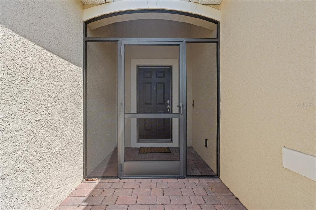 A dark front door is enclosed by a screen door within a covered entryway — 8932 EXCELSIOR PLACE, VENICE, FL