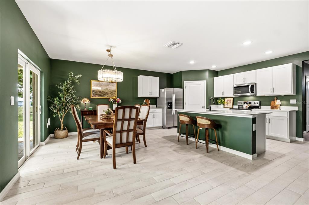 A kitchen and dining area featuring green walls, white cabinets, and a central island — 25479 ORESTO COURT, PUNTA GORDA, FL