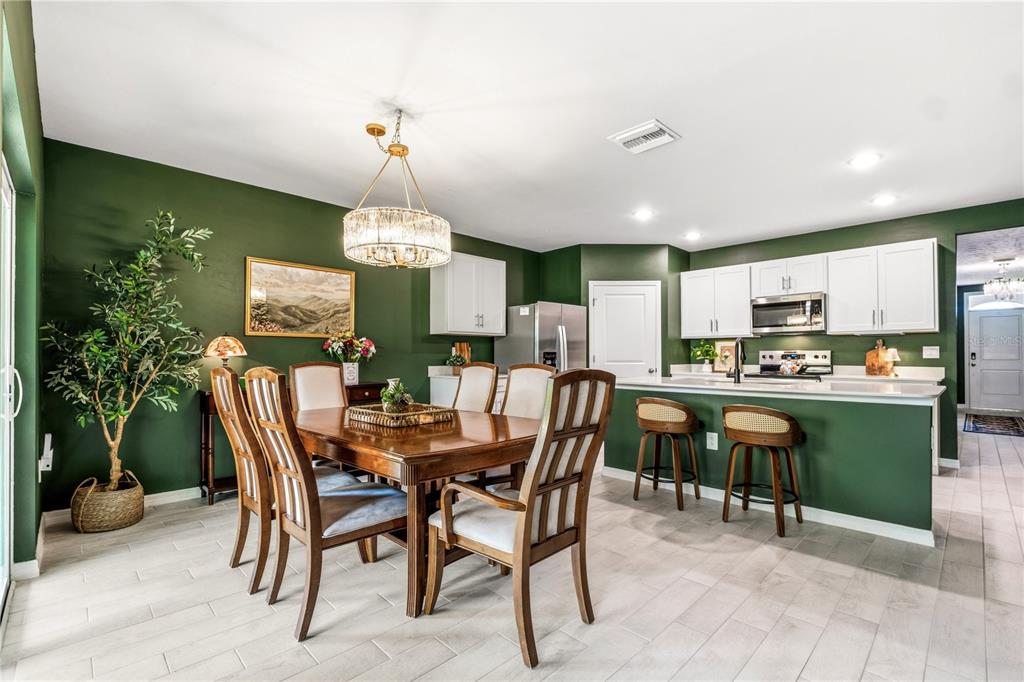 A dining area and kitchen feature dark green walls, white cabinets, and a wooden table — 25479 ORESTO COURT, PUNTA GORDA, FL