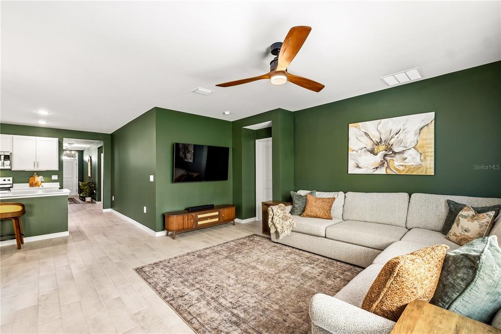 A living room with green walls, a sectional sofa, a television, and a ceiling fan — 25479 ORESTO COURT, PUNTA GORDA, FL