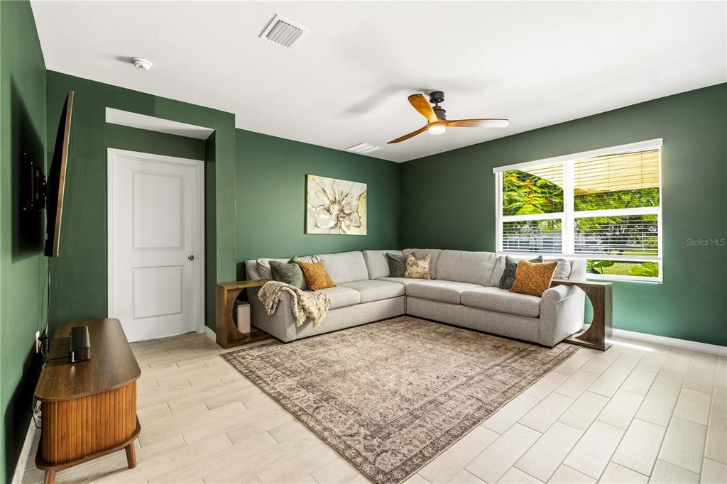 A living room features green walls, a light gray sectional sofa, and a large area rug — 25479 ORESTO COURT, PUNTA GORDA, FL