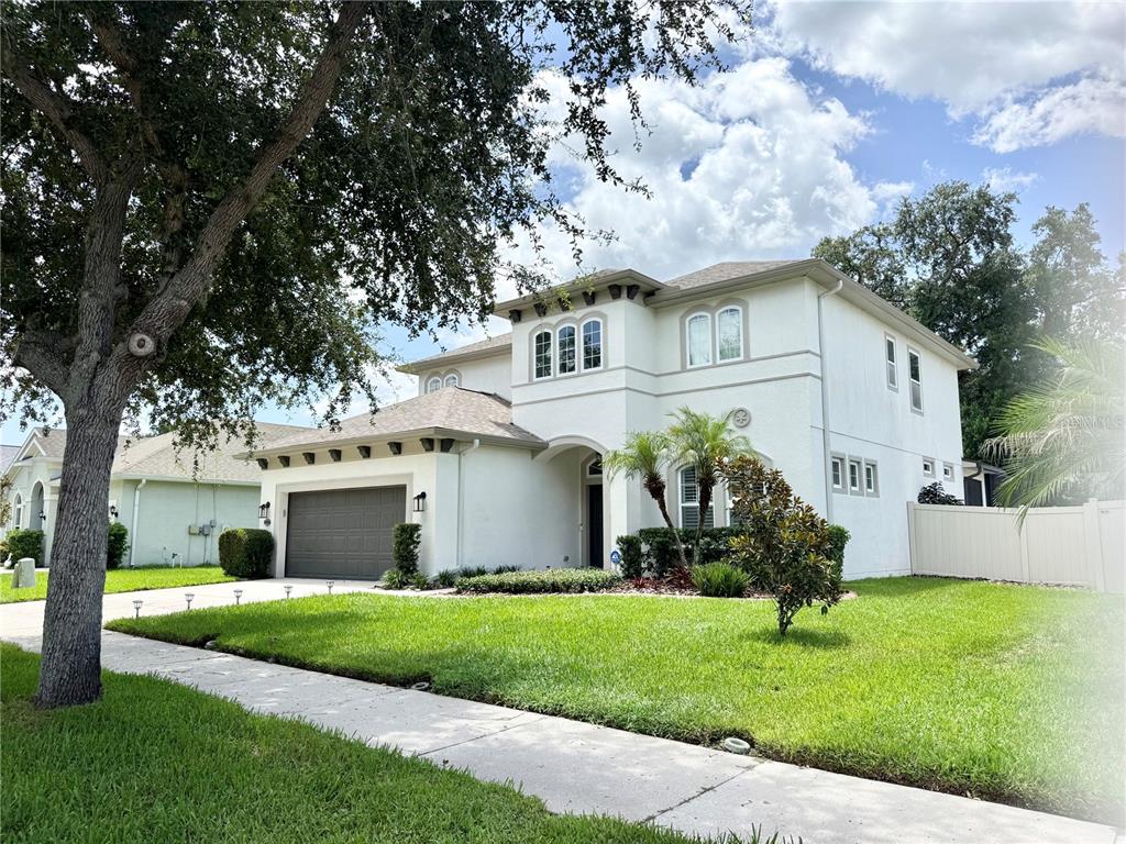 A two-story, light-colored stucco house with a two-car garage and a front lawn — 212 MONTARA DRIVE, SEFFNER, FL