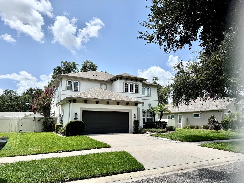 A two-story house with a dark garage door, light-colored stucco, and a concrete driveway — 212 MONTARA DRIVE, SEFFNER, FL