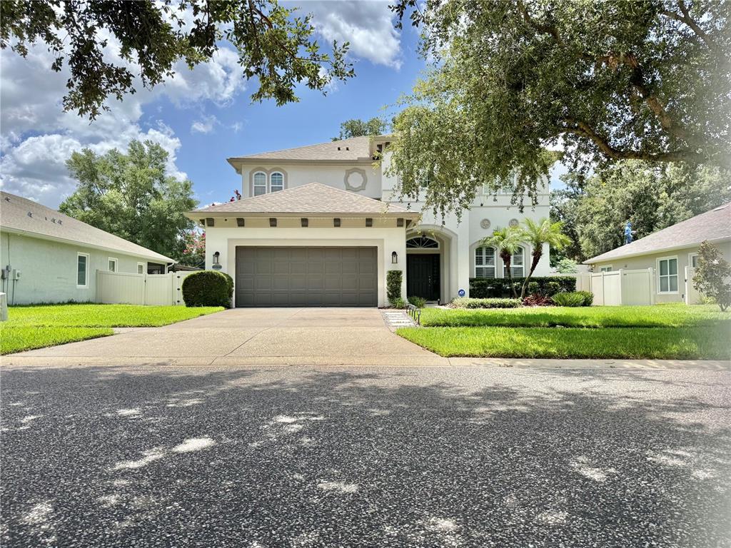 A two-story house with a beige stucco exterior, a gray garage door, and a concrete driveway — 212 MONTARA DRIVE, SEFFNER, FL