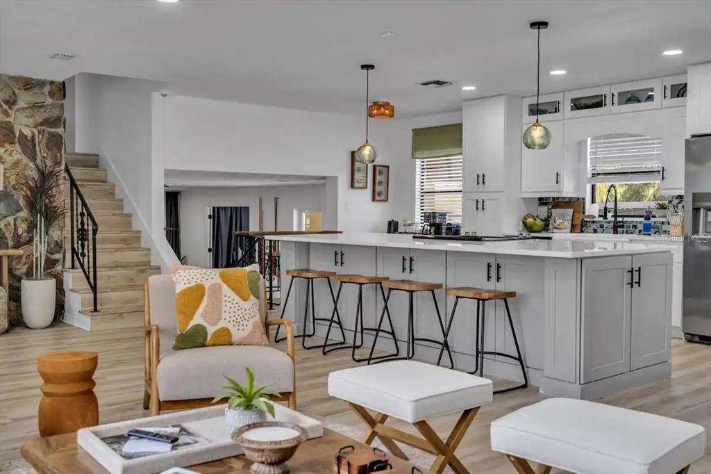 A modern kitchen with a large island and bar stools overlooks a living area — 14389 83RD PLACE, SEMINOLE, FL