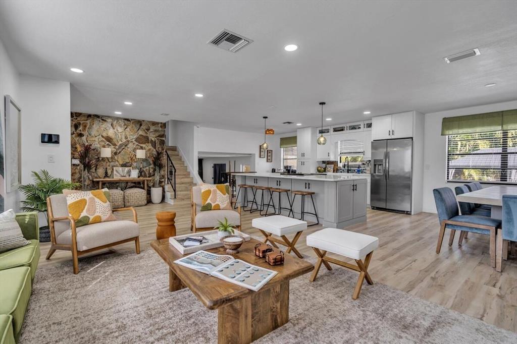 An open-concept living room and kitchen featuring a stone accent wall and wood flooring — 14389 83RD PLACE, SEMINOLE, FL