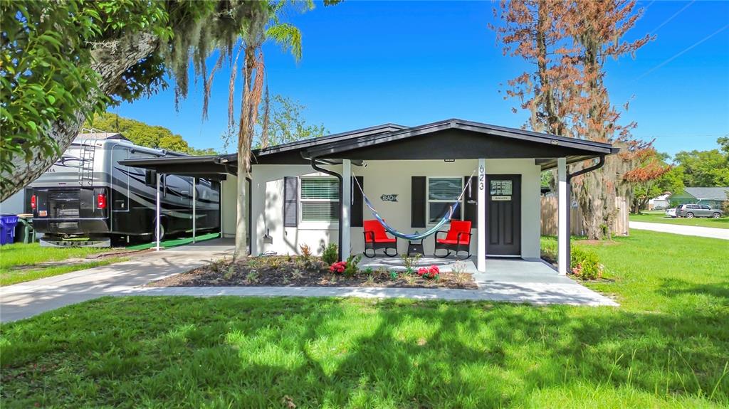 A single-story house with a covered front porch, two red chairs, and a hammock — 623 JERSEY AVENUE, ST CLOUD, FL