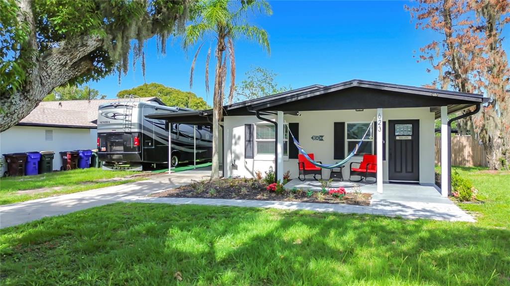 A single-story house with a covered porch, a hammock, and an RV parked in the driveway — 623 JERSEY AVENUE, ST CLOUD, FL