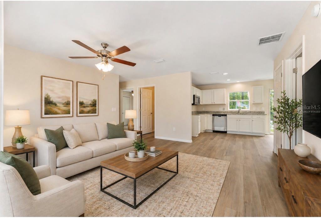 A living room with a sofa and coffee table opens to a kitchen with white cabinets — 467 SW ALVAREZ ROAD, DUNNELLON, FL