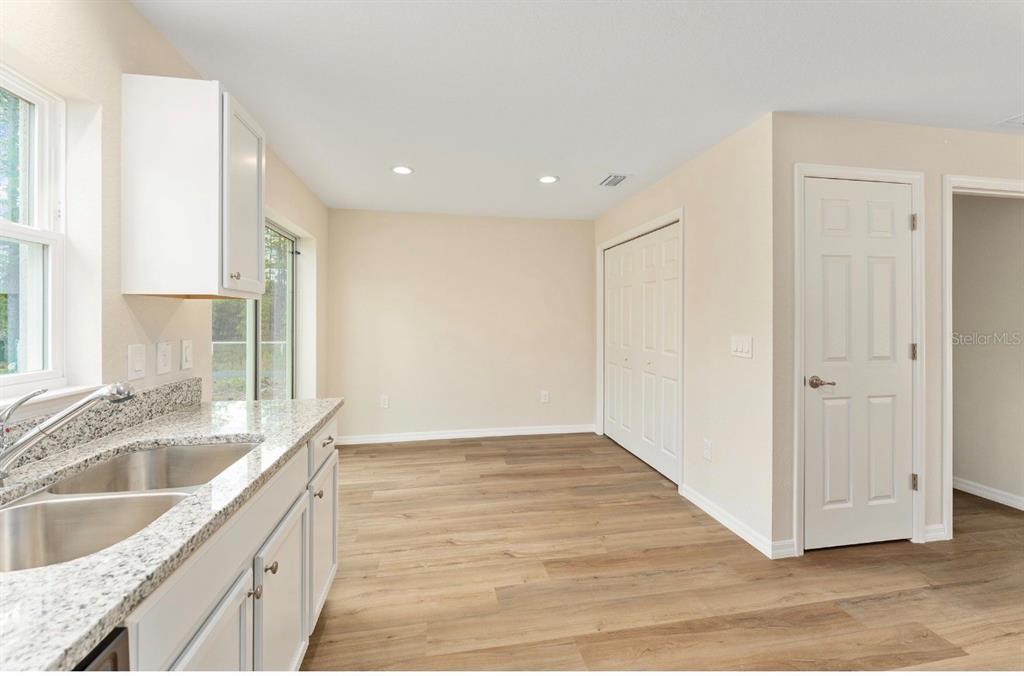 A kitchen area features light wood-look flooring, white cabinets, granite countertops, and a double sink — 467 SW ALVAREZ ROAD, DUNNELLON, FL