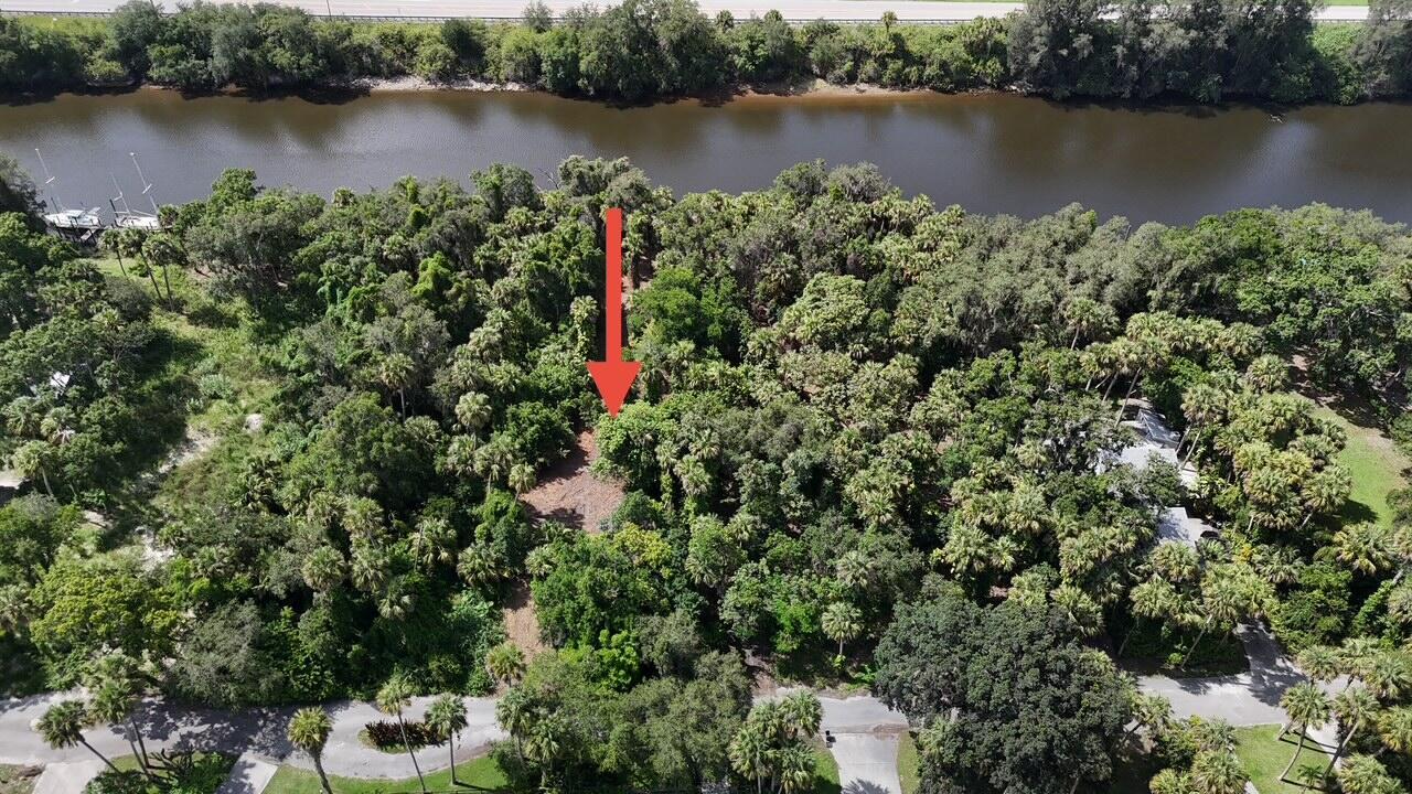 An aerial view shows a wooded lot with a cleared area near a riverbank — 14560 SW Sonora Terrace, FL 34956, FL