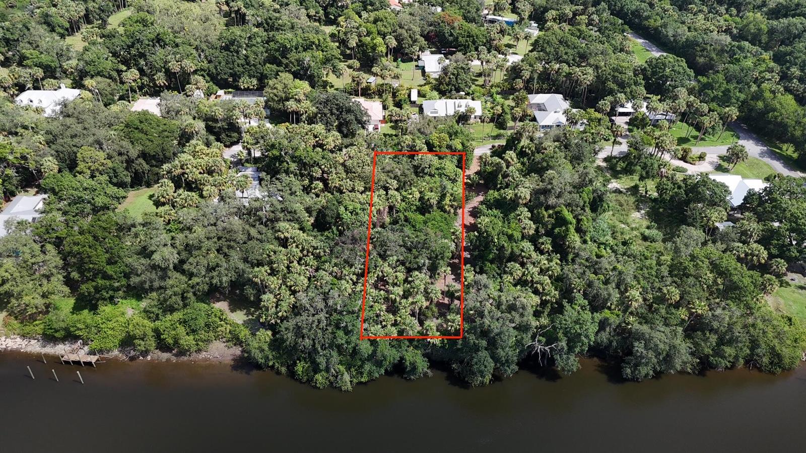 An aerial view shows a rectangular wooded lot bordering a river in a residential area — 14560 SW Sonora Terrace, FL 34956, FL