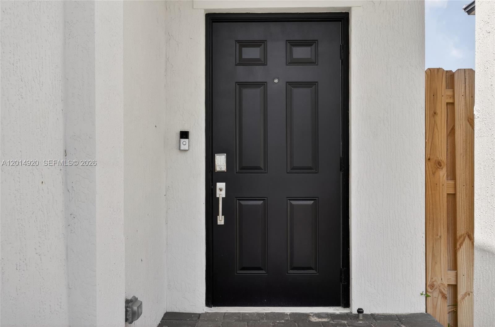 A black front door with a smart doorbell and keypad lock is set in a wall — 4981 Peacock Way, Dania Beach FL 33312, DANIA BEACH, FL