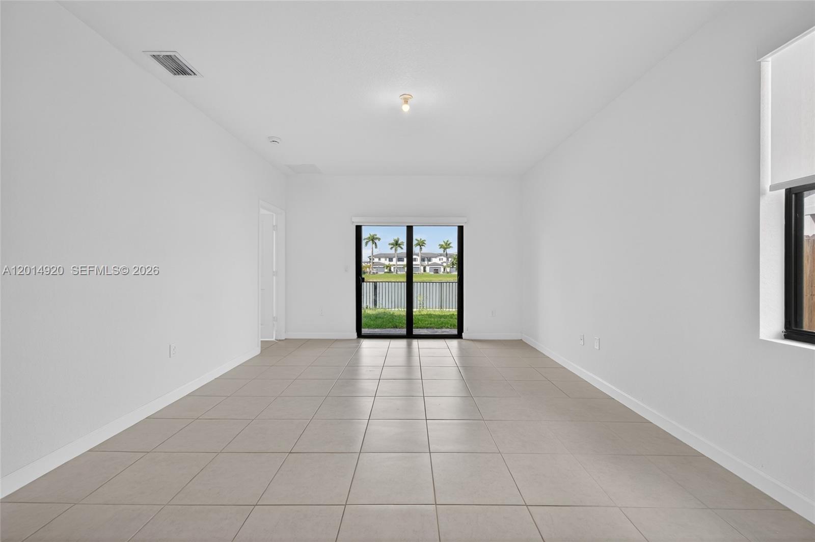 A tiled room with a sliding glass door leads to a small bathroom with a pedestal sink — 4981 Peacock Way, Dania Beach FL 33312, DANIA BEACH, FL
